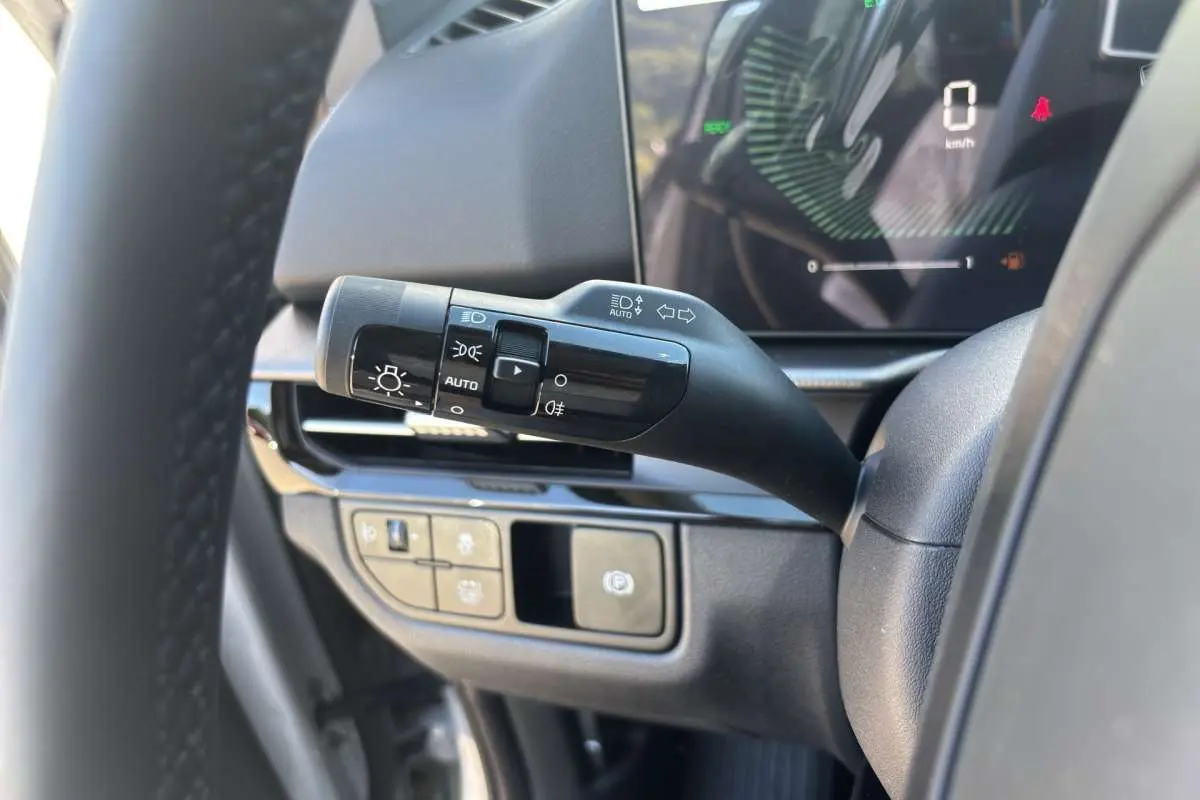 Gros plan sur la commande des feux et tableau de bord numérique du Kia Sportage gris céramique, version 2026.