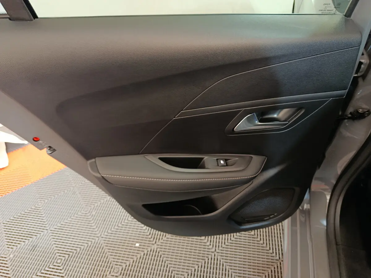 Vue rapprochée de la porte avant droite gris foncé du Peugeot 208 PureTech 100 S&S Allure avec commande de vitre et haut-parleur intégré