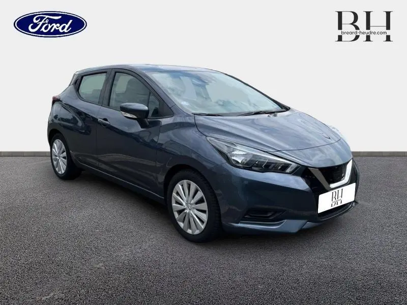 Vue 3/4 avant droite d'une Nissan Micra gris acier 2022 avec phares anguleux et jantes en alliage simple.