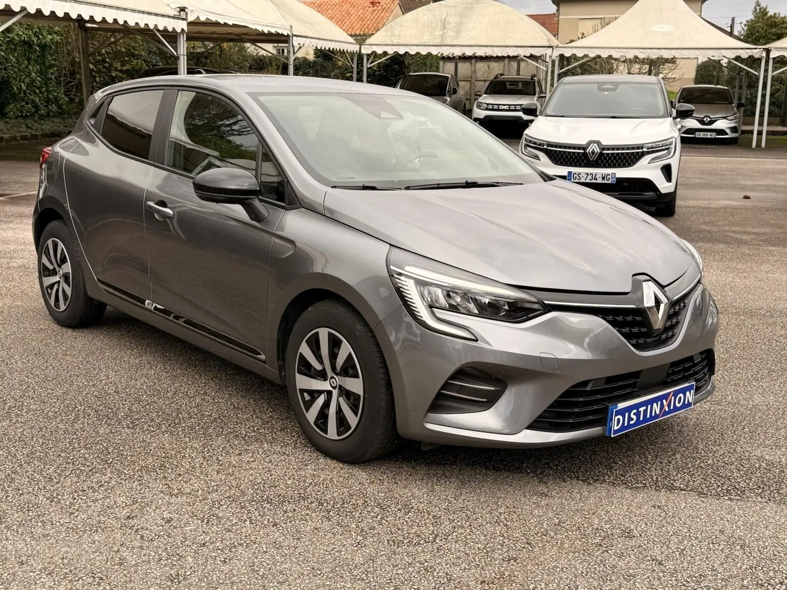 Renault Clio V gris schiste vue 3/4 avant droit, mettant en valeur ses phares LED et jantes bi-ton 16 pouces.