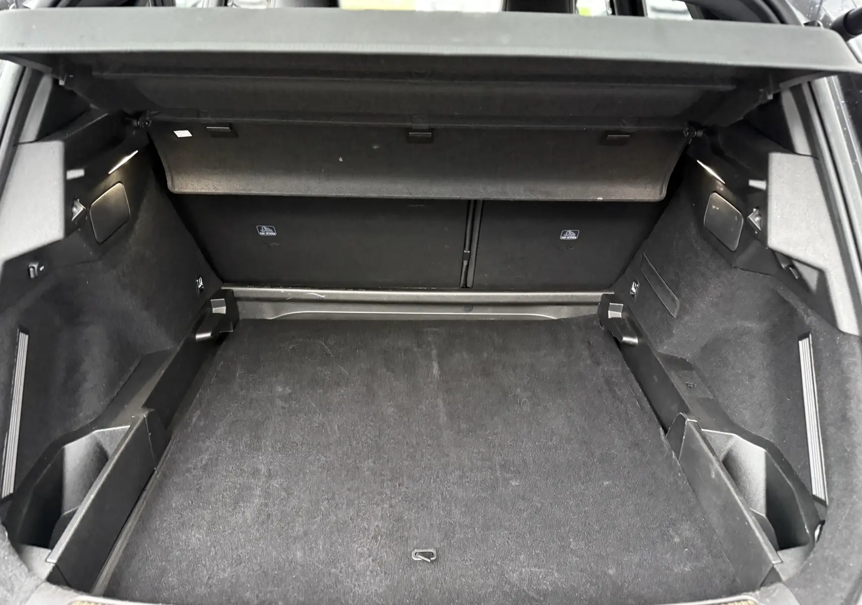 Coffre ouvert vu de l'arrière d'un DS7 gris titane, montrant un espace de chargement propre et bien agencé.