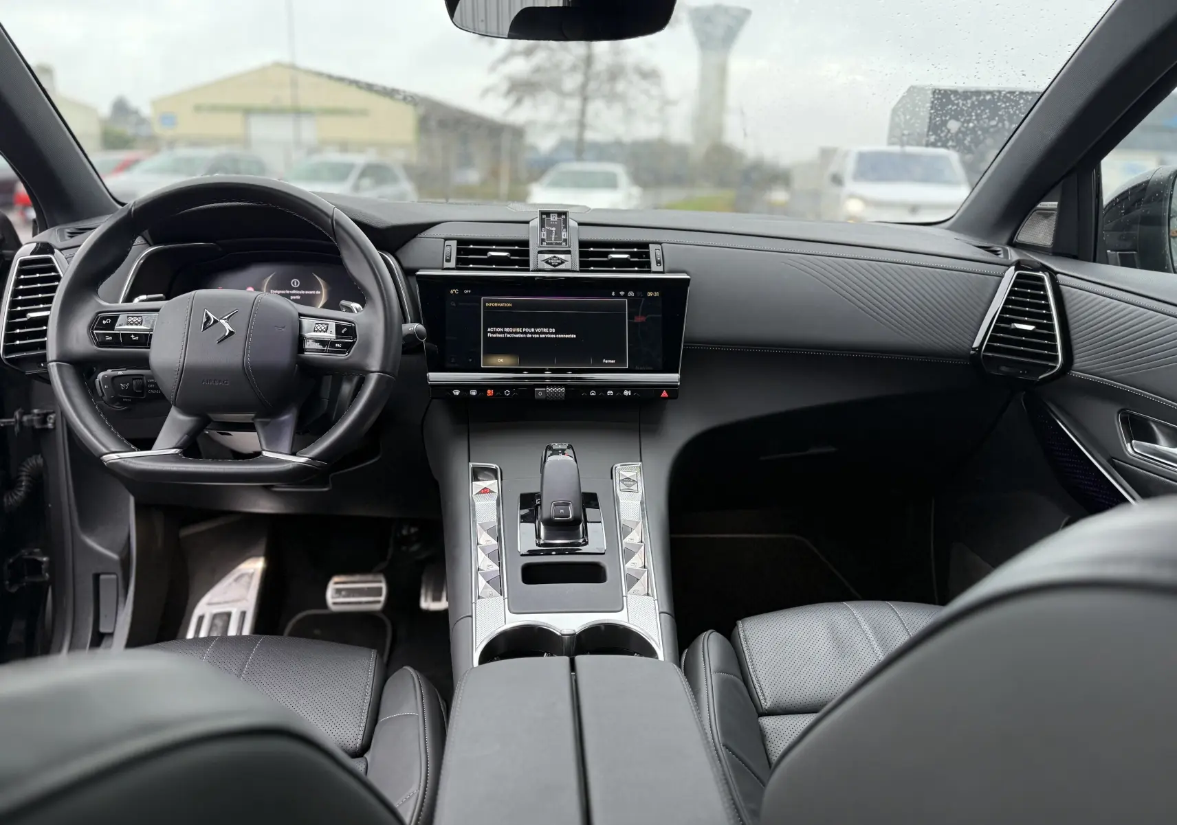 Vue intérieure avant du DS7 2025 gris titane, avec tableau de bord moderne et volant multifonction en cuir noir.