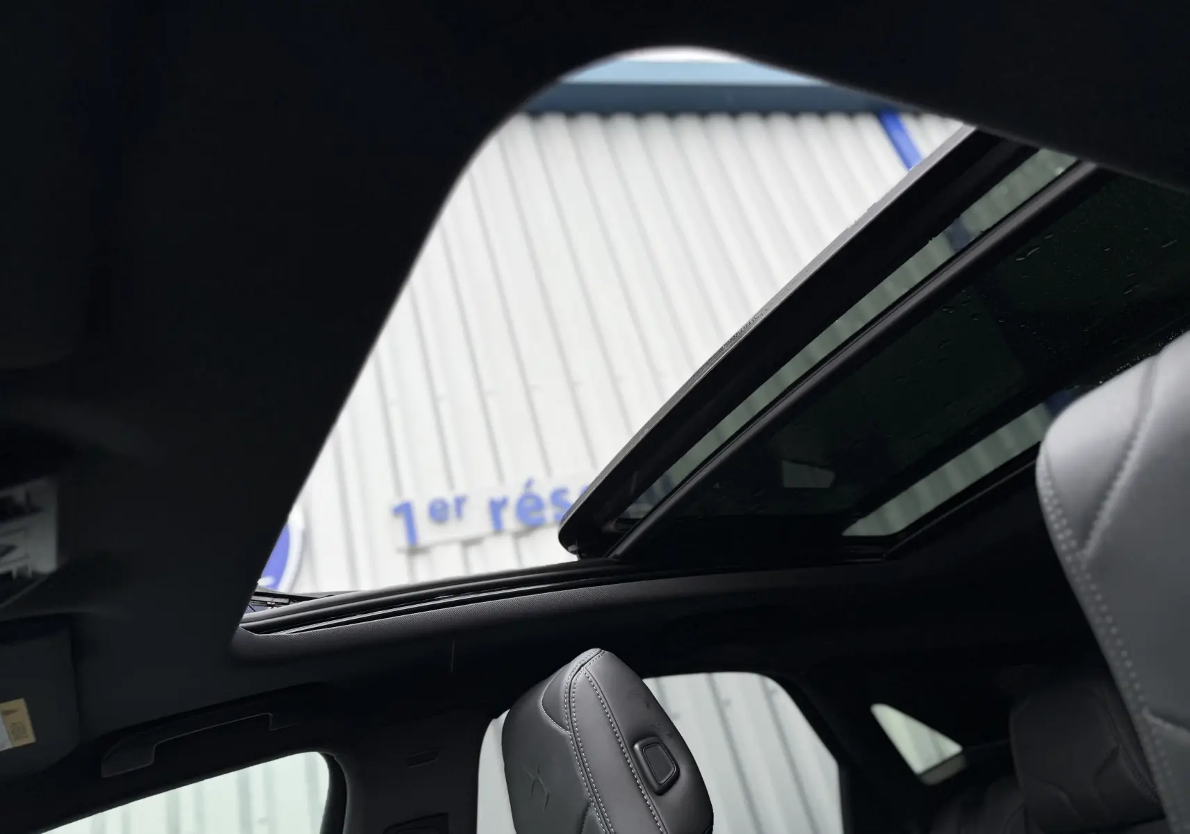 Vue intérieure du toit ouvrant électrique du DS7 gris titane, avec sièges avant en cuir visibles.