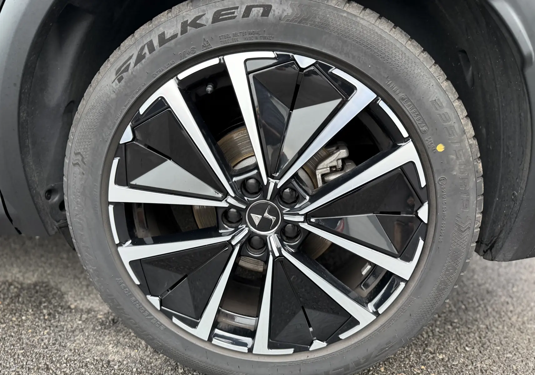 Gros plan sur la roue avant droite du DS7 2025 gris titane, jante alliage noir et argent au design géométrique.
