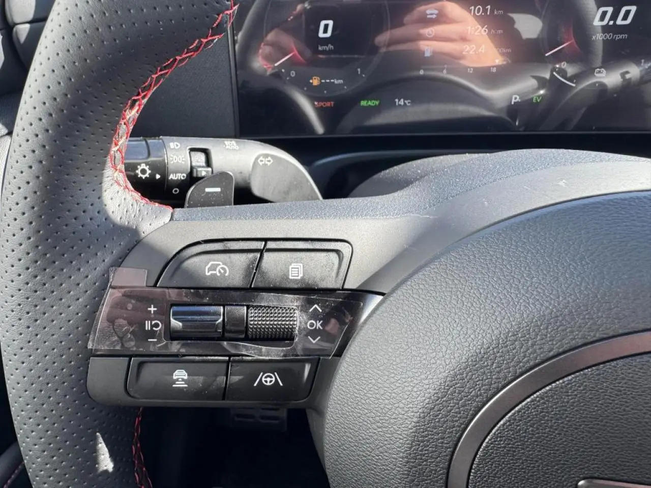 Gros plan sur le volant cuir noir avec surpiqûres rouges du Hyundai Tucson N Line 2025, affichage numérique en arrière-plan.