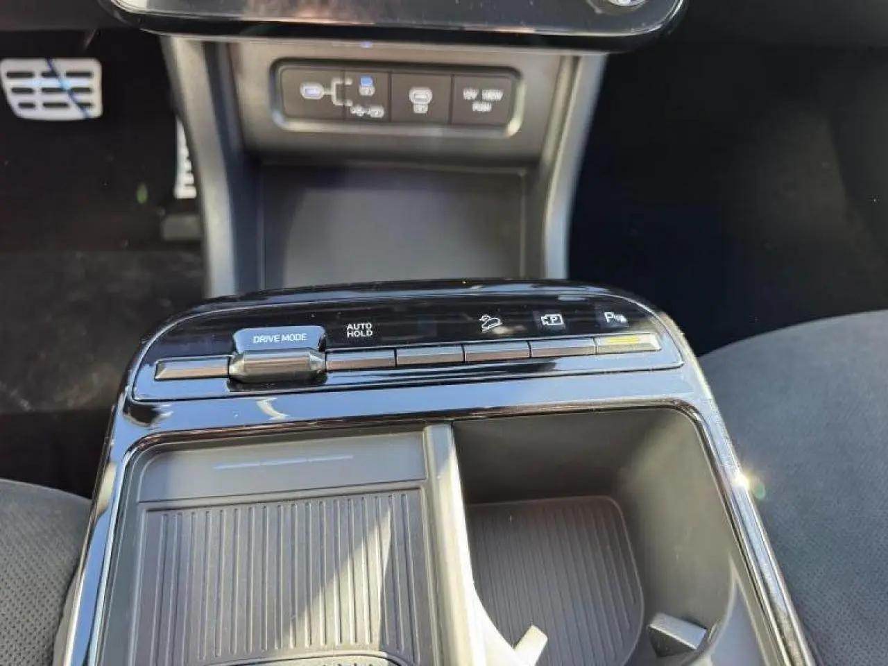 Gros plan sur la console centrale noire brillante du Hyundai Tucson 2025, avec commandes Drive Mode et Auto Hold visibles.
