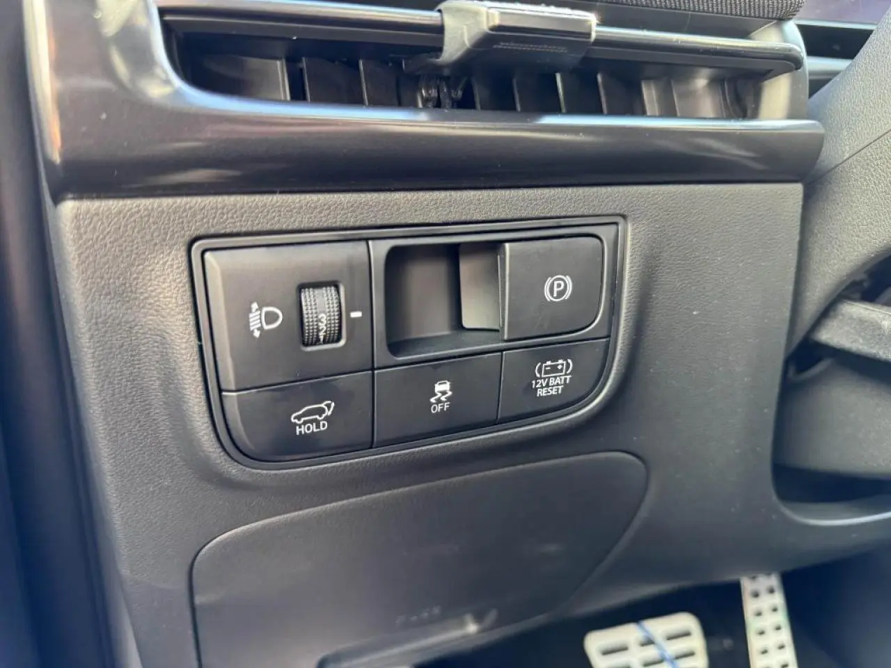 Gros plan sur les commandes côté gauche du tableau de bord du Hyundai Tucson noir, avec régulateur de frein de parking et ajustement des phares.