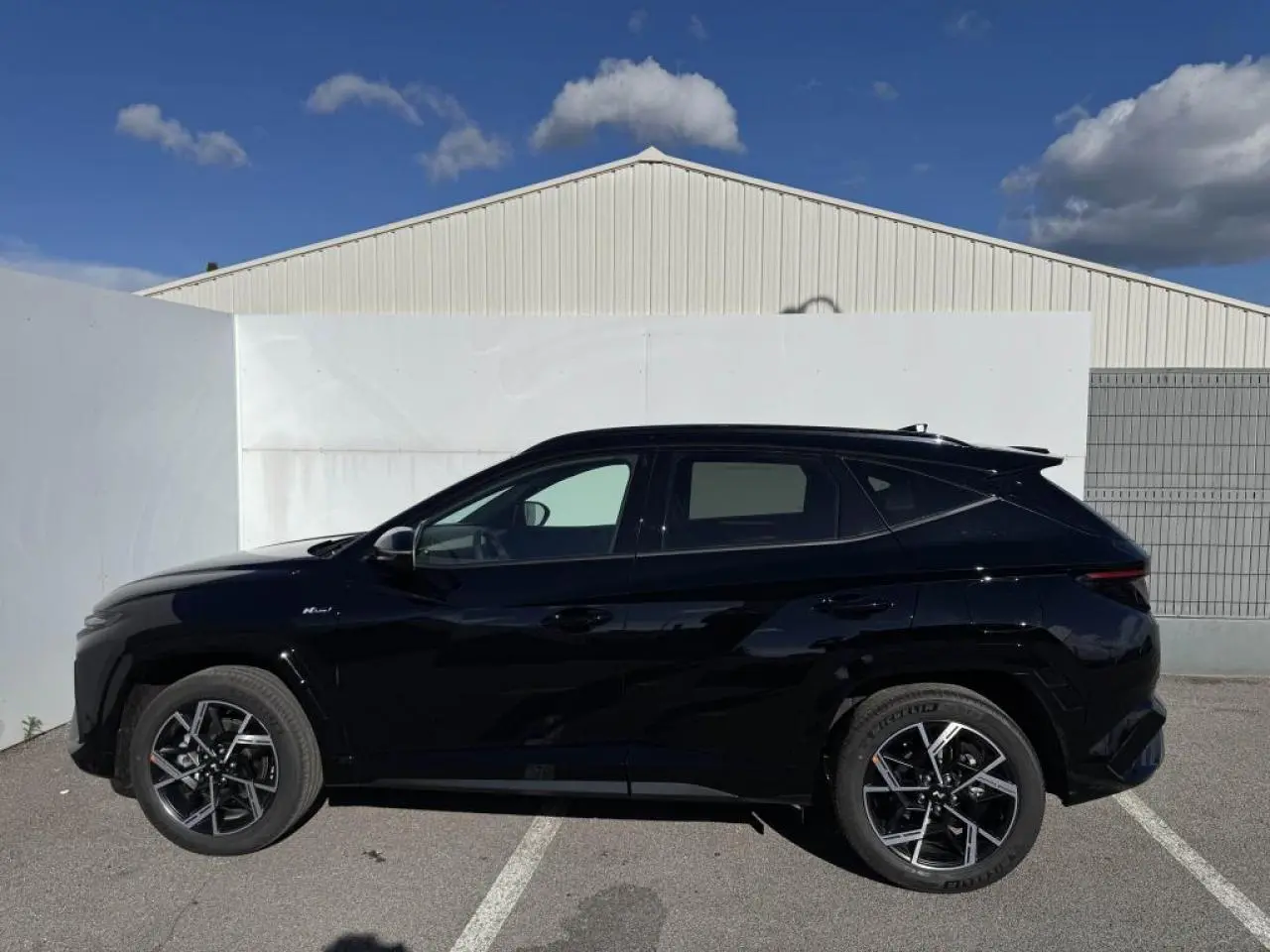 Vue latérale droite du Hyundai Tucson 2025 noir Abyss Metal avec jantes alliage 19'' N Line et vitres surteintées.