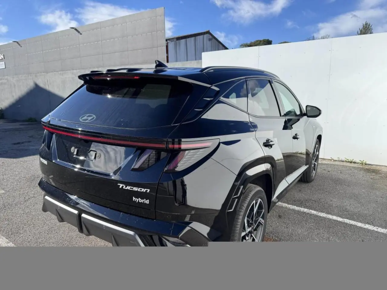 Vue 3/4 arrière droite du Hyundai Tucson noir abyss métallisé avec feux arrière LED et jantes alliage 19 pouces N Line.