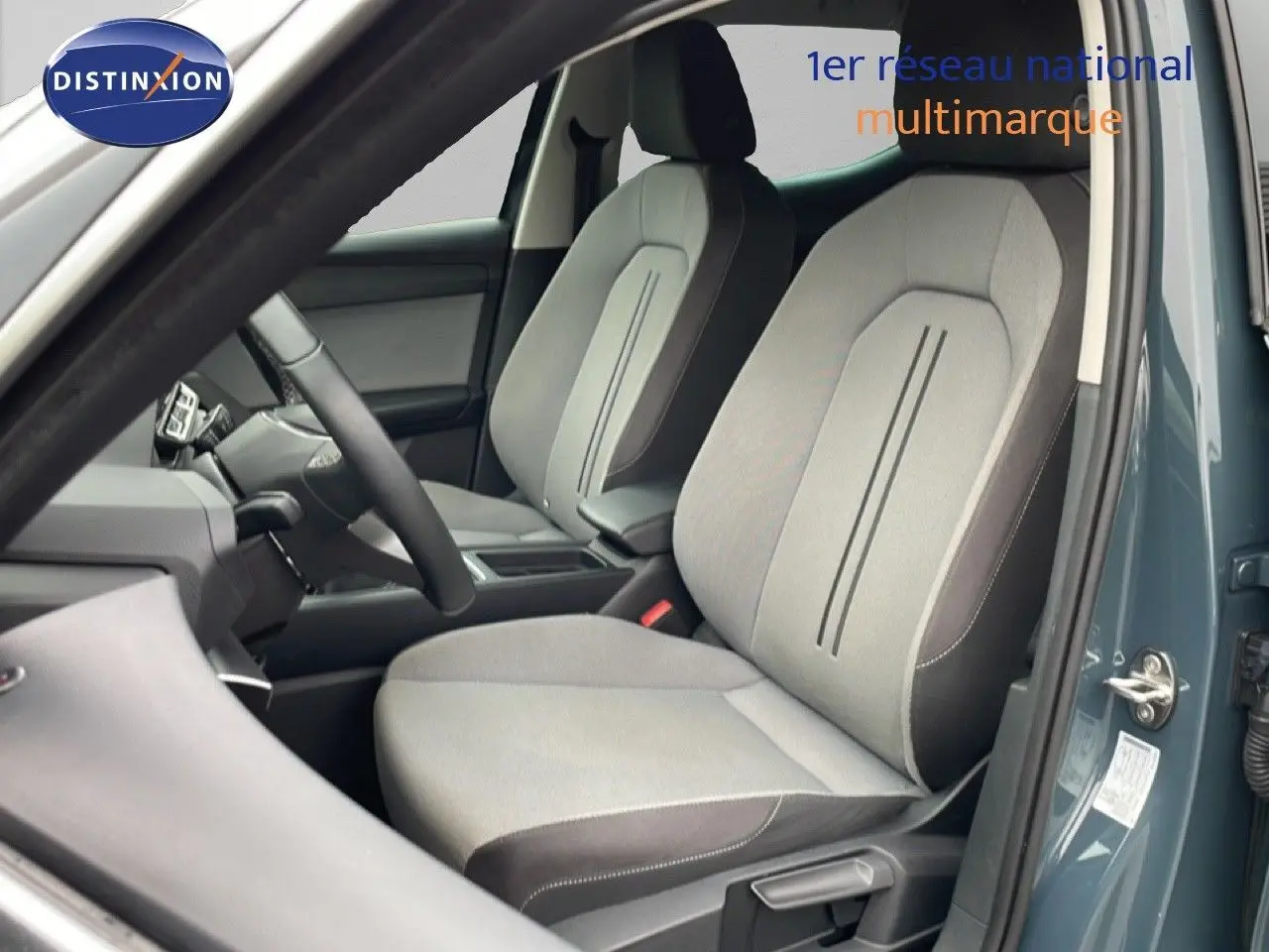 Vue intérieure côté conducteur du SEAT Leon 2025 bleu Fjord, mettant en valeur les sièges tissu gris clair avec contours foncés.