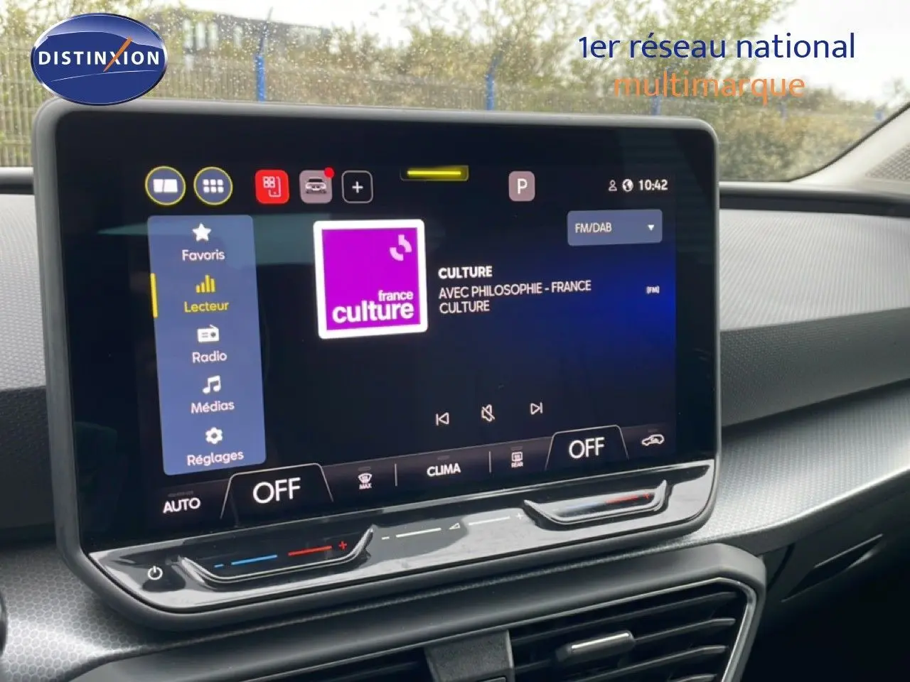 Vue rapprochée de l’écran tactile central du tableau de bord du SEAT LEON 2.0 TDI bleu Fjord, affichant une radio FM.