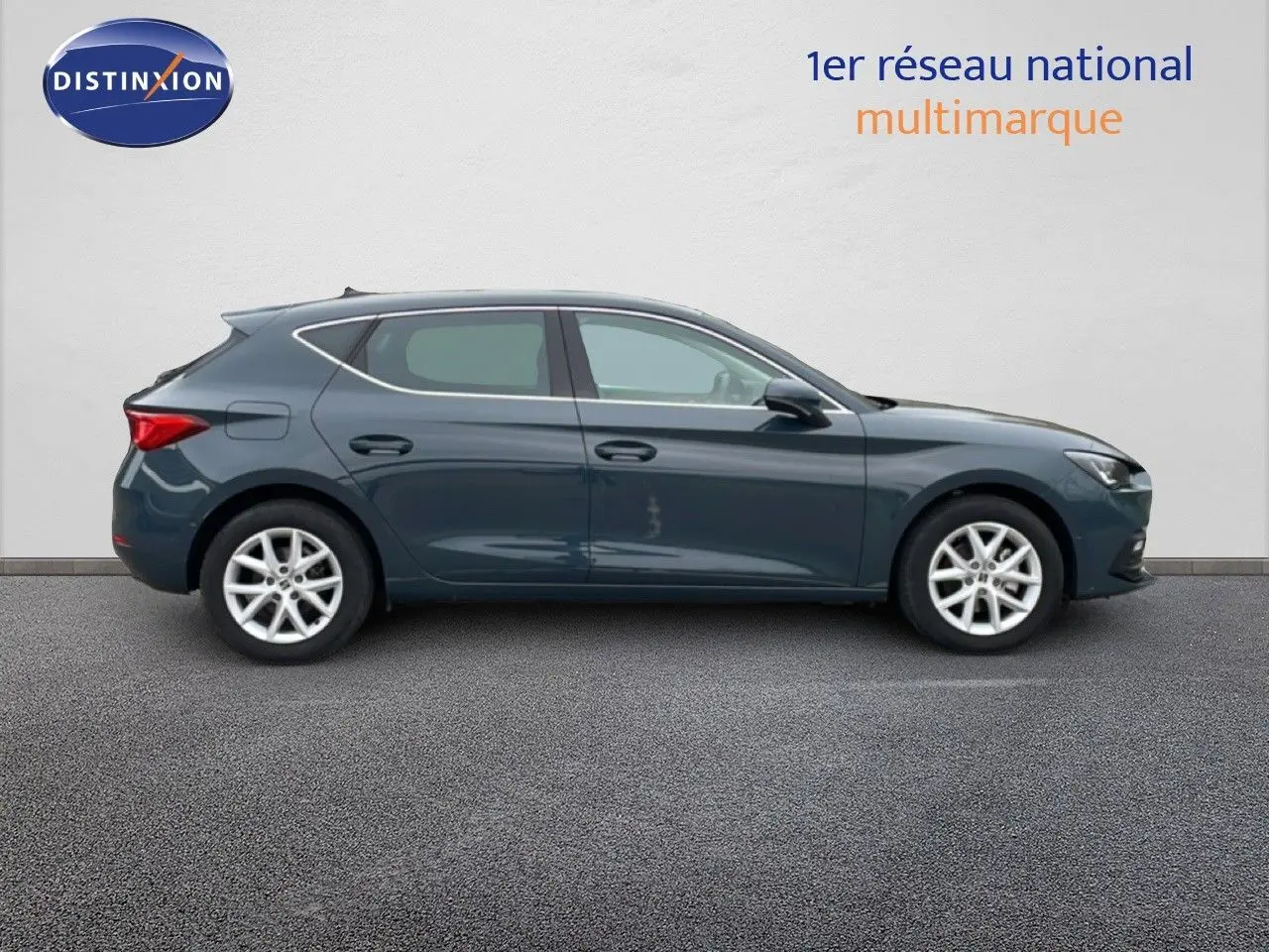 Vue latérale droite d'une SEAT LEON 2.0 TDI 115CH STYLE XL en bleu fjord, garée sur sol gris devant un mur clair.