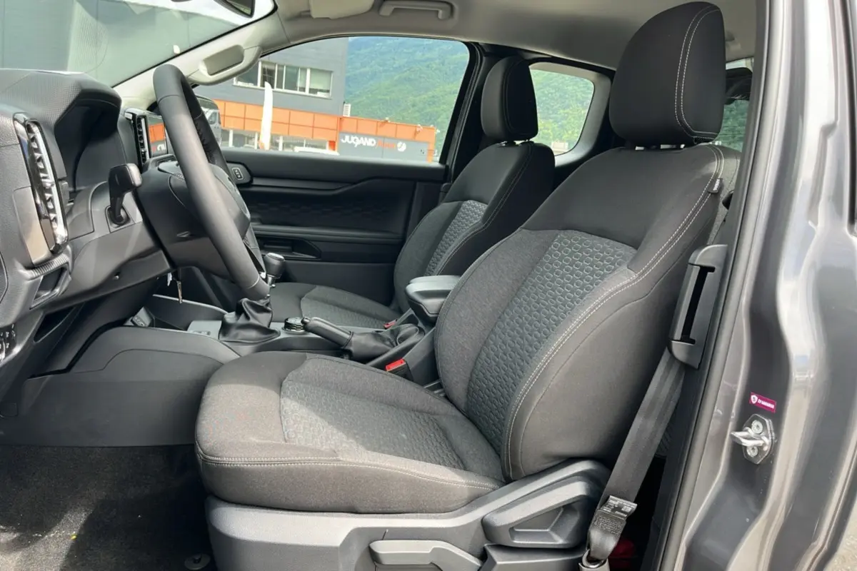 Vue intérieure côté conducteur du Ford Ranger gris carbone 2025, montrant les sièges tissu et le volant multifonctions cuir.