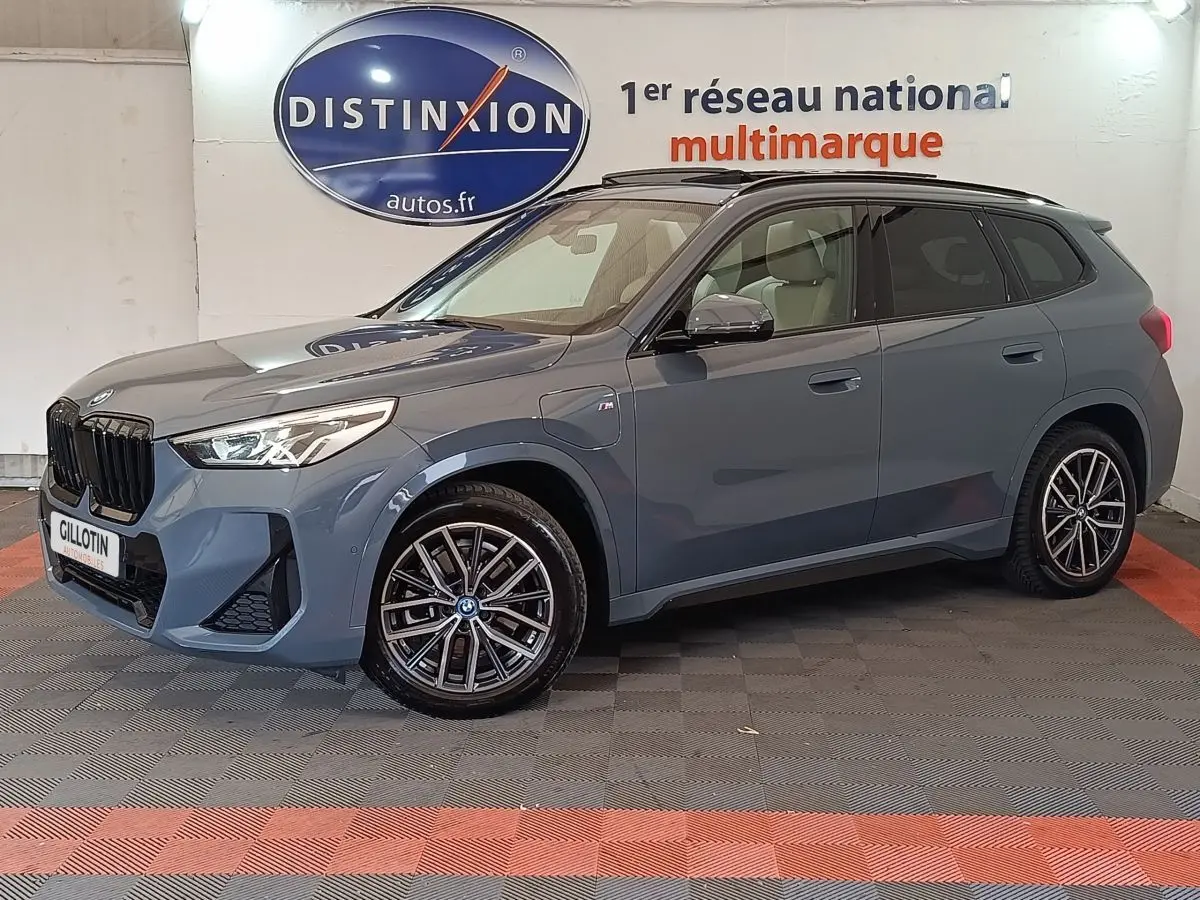 BMW X1 xDrive25e M Sport gris foncé vue de profil droit en intérieur avec jantes alliage et toit noir.