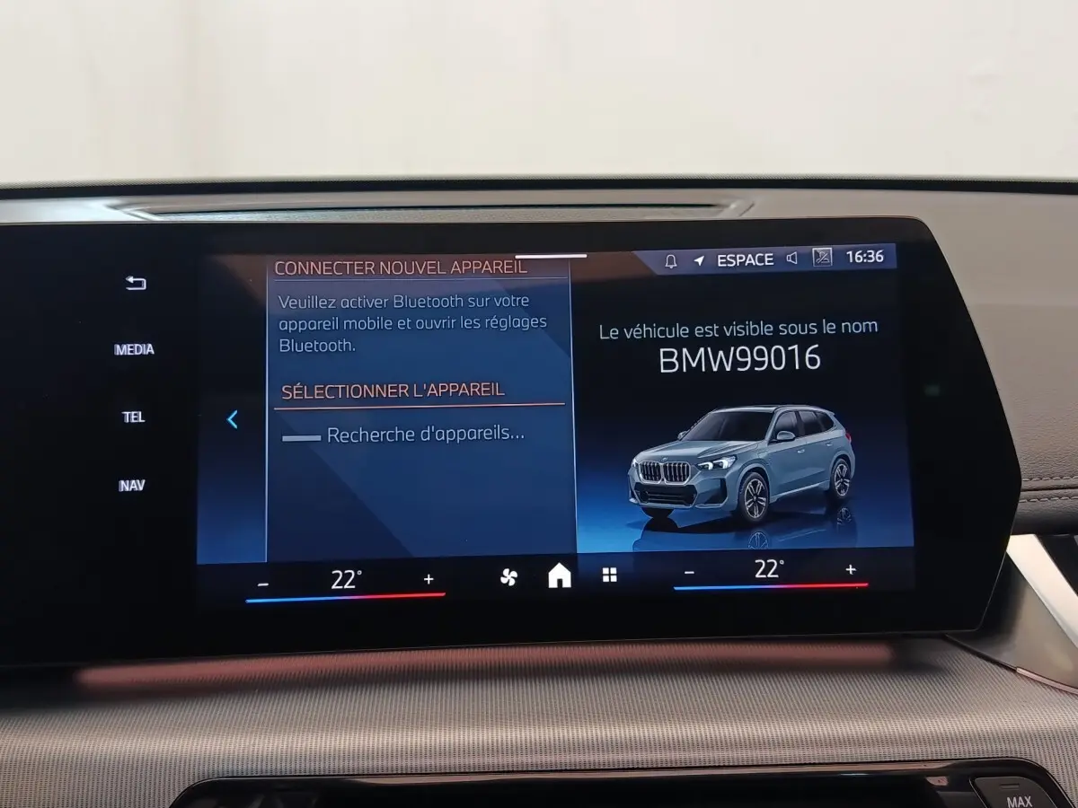 Écran tactile central affichant un BMW X1 gris foncé en 3/4 avant droit dans l'interface multimédia.