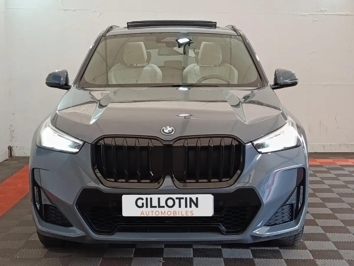 Vue frontale d'un BMW X1 xDrive25e M Sport gris foncé avec calandre noire et phares LED allumés.