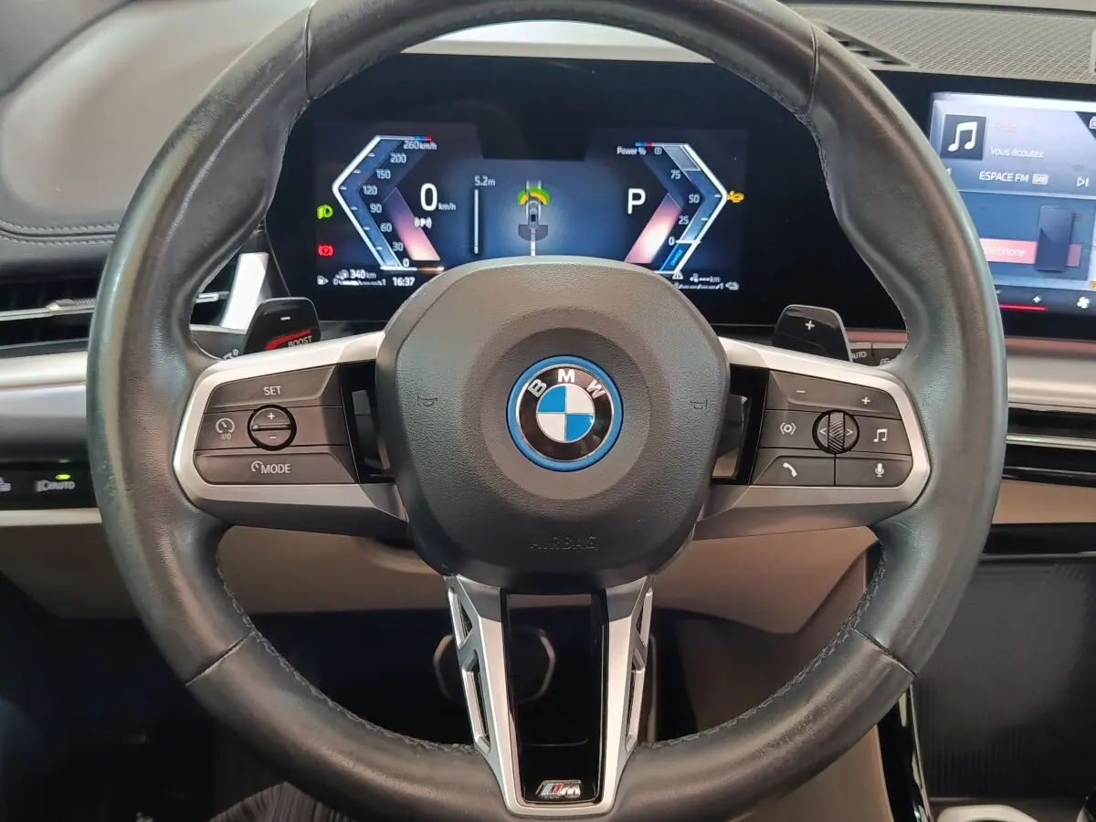 Vue rapprochée du volant cuir M Sport et du combiné numérique 10,25 pouces du BMW X1 xDrive25e gris foncé 2024.