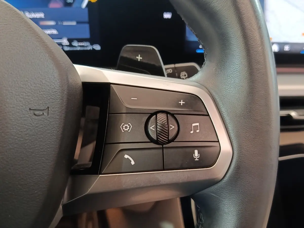 Gros plan sur les commandes multifonctions du volant cuir noir du BMW X1 xDrive25e M Sport 2024.