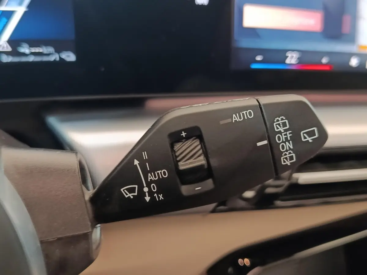 Gros plan sur la commande d’essuie-glace du BMW X1 xDrive25e M Sport gris foncé, avec affichage digital en arrière-plan.