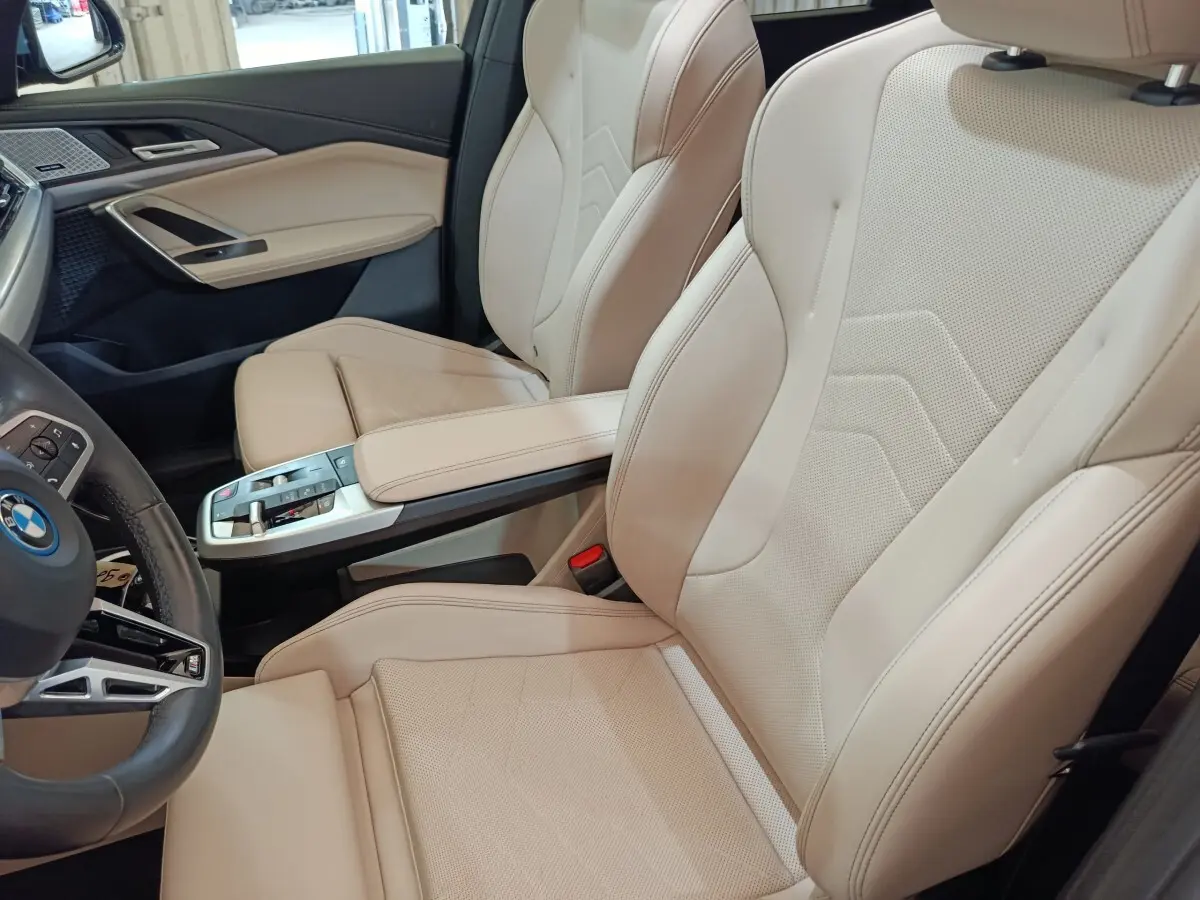 Vue intérieure côté conducteur du BMW X1 xDrive25e 2024, sièges cuir beige et console centrale moderne.