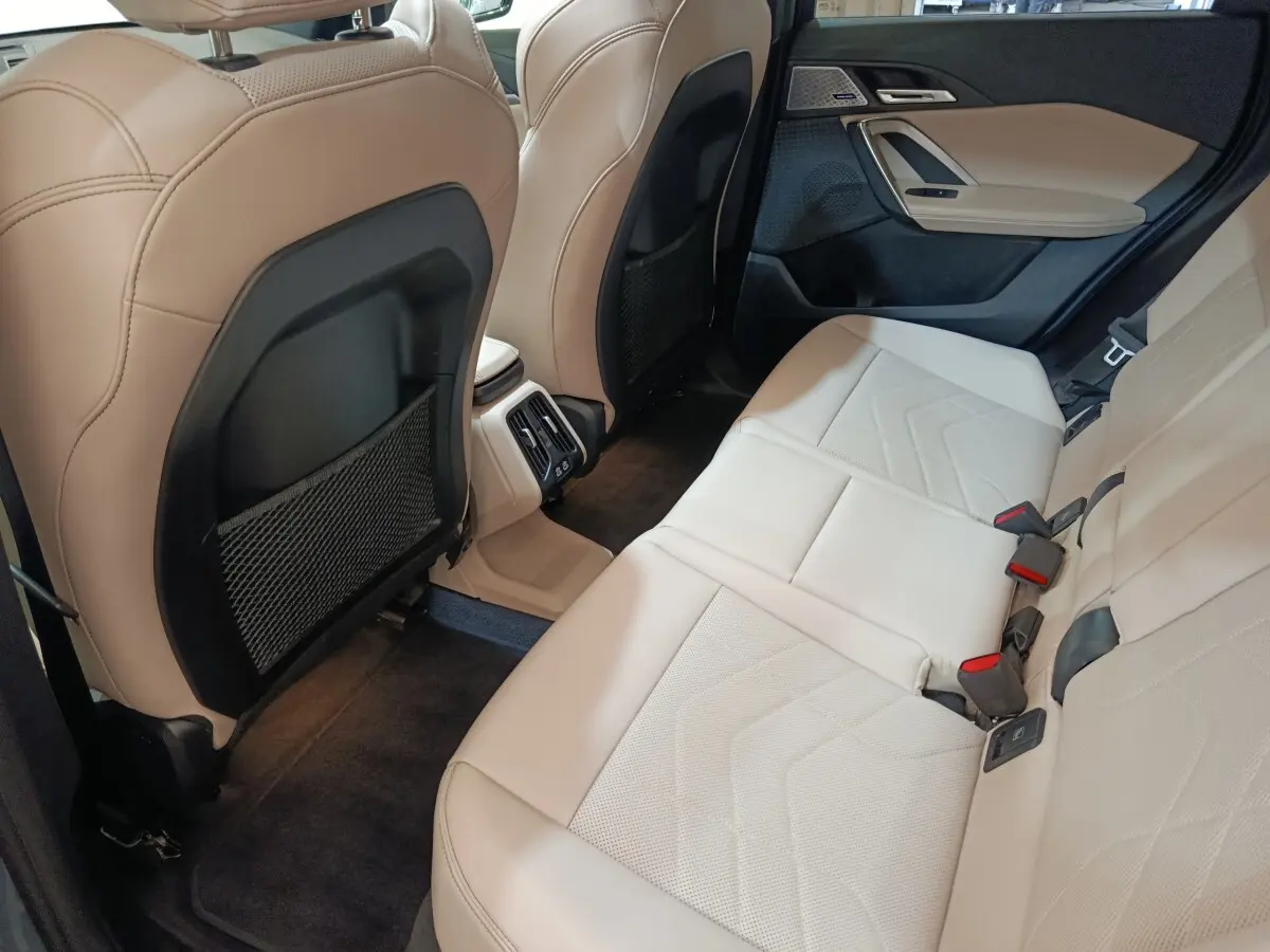 Vue intérieure arrière côté droit du BMW X1 xDrive25e M Sport 2024, sièges cuir beige et détails noirs.