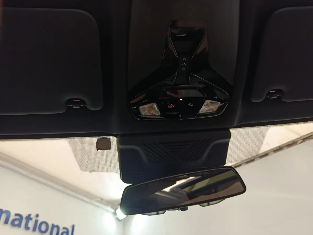 Vue intérieure centrée sur le plafonnier noir et le rétroviseur intérieur d'une BMW X1 gris foncé 2024.