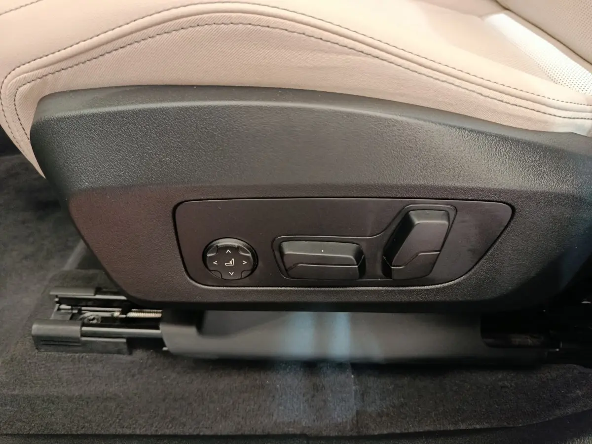 Détail des commandes électriques de réglage du siège avant beige dans un BMW X1 xDrive25e M Sport gris foncé 2024.