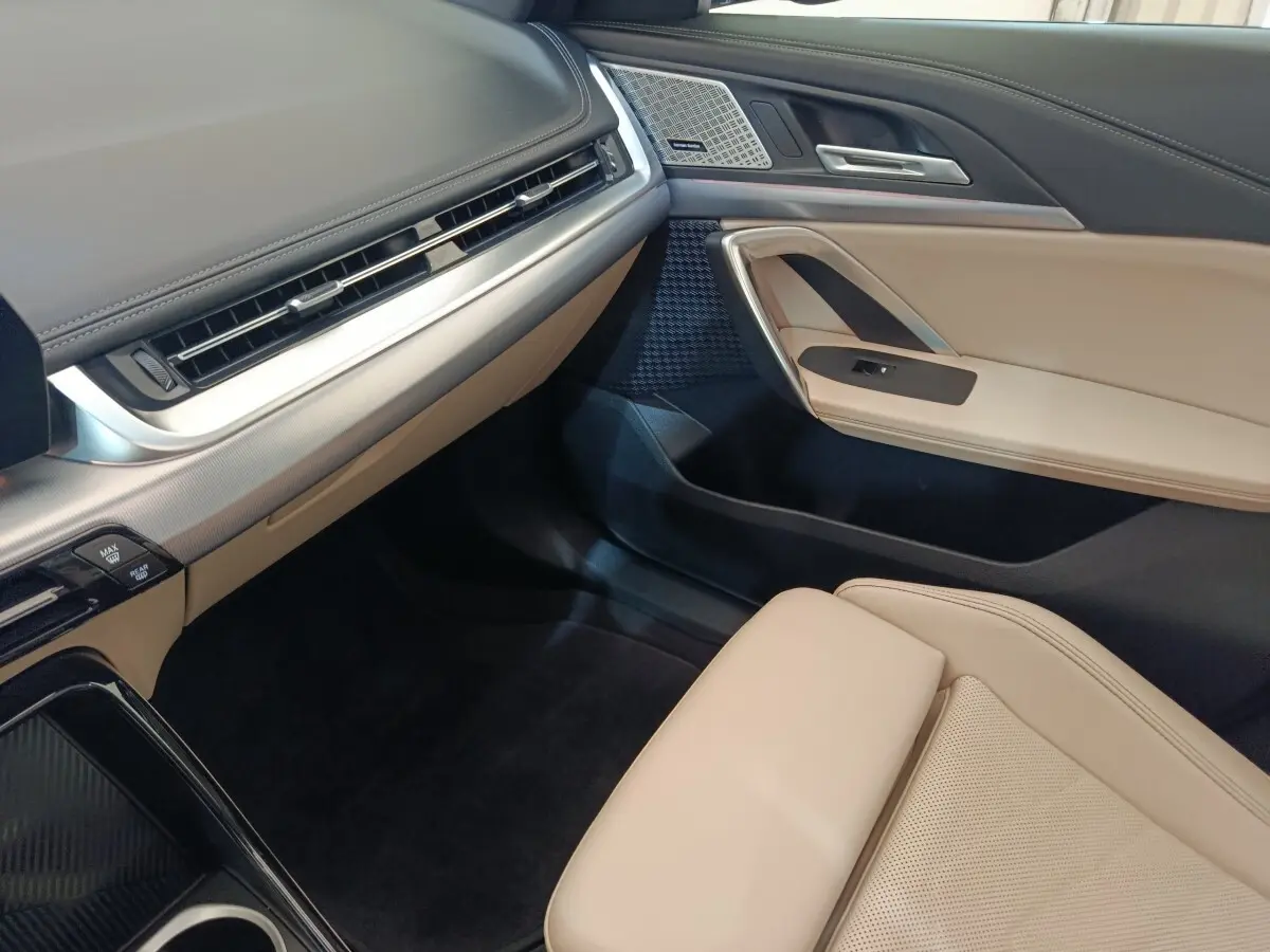 Intérieur avant droit du BMW X1 xDrive25e 2024, avec sellerie beige, tableau de bord noir et inserts aluminium.