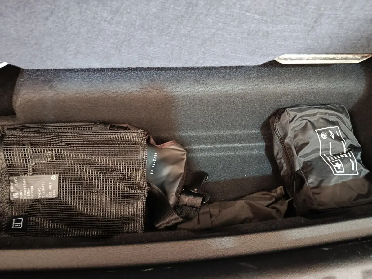 Compartiment de rangement sous plancher dans un BMW X1 xDrive25e M Sport gris foncé, avec trousse de secours et équipement.