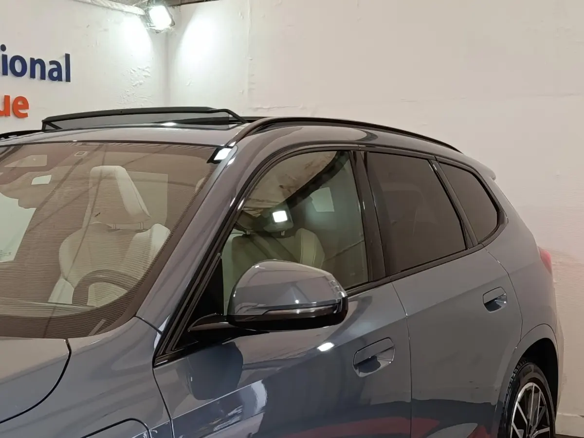 Vue de côté droit d'un BMW X1 xDrive25e M Sport gris foncé avec rétroviseur et vitres teintées visibles.