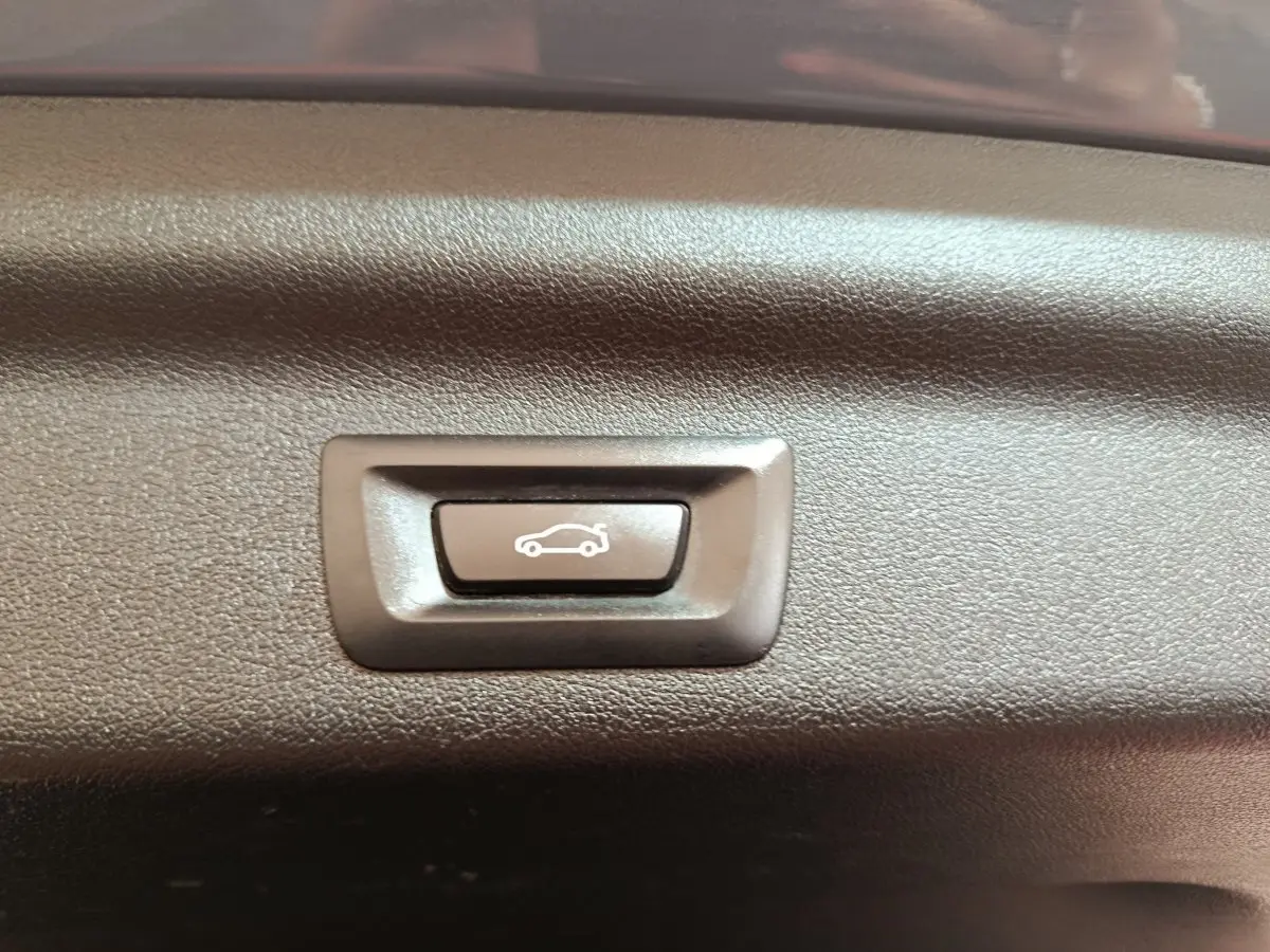 Bouton d'ouverture électrique du coffre sur panneau intérieur d'une BMW X1 xDrive25e M Sport gris foncé 2024.