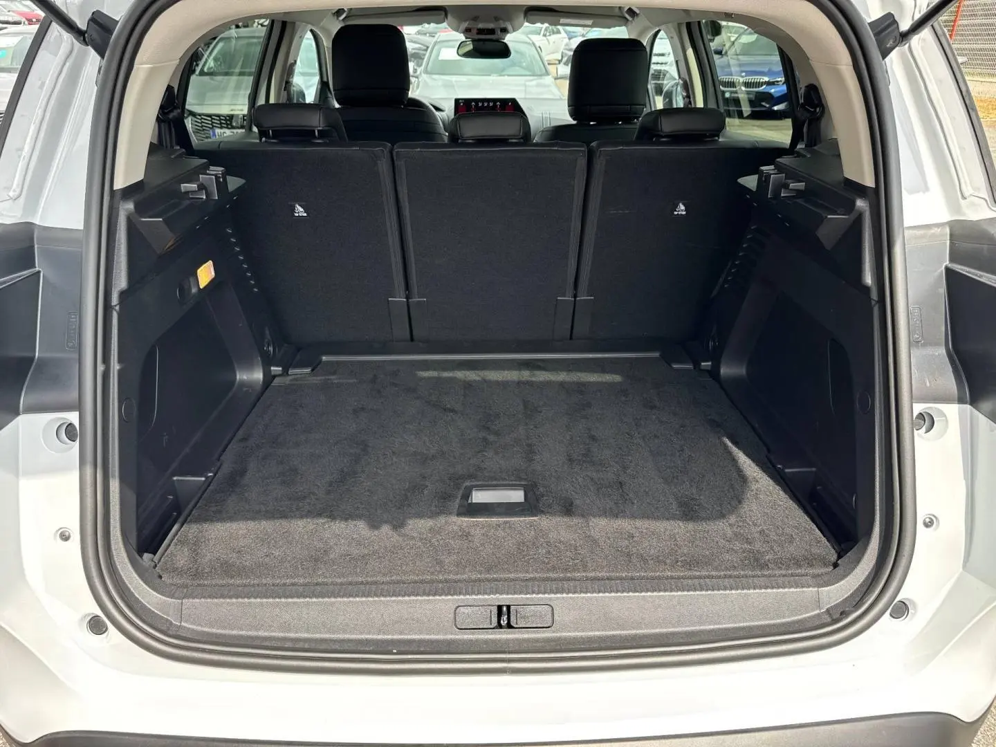Coffre ouvert vu de l'arrière d'un Citroën C5 Aircross blanc Okénite avec sièges arrière en tissu noir relevés.
