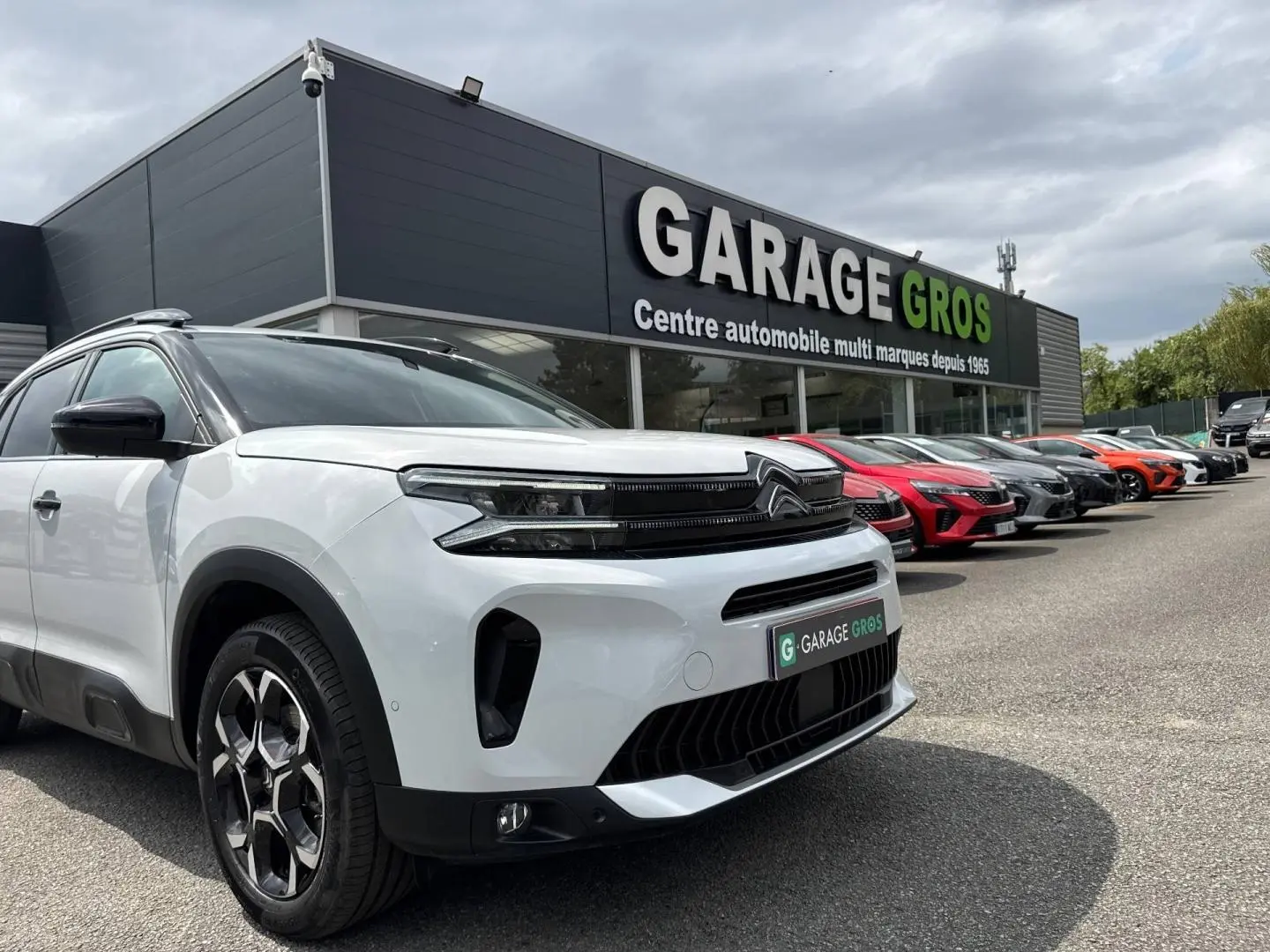 Citroën C5 Aircross blanc Okénite vue 3/4 avant droit avec calandre noire et jantes alu au garage.