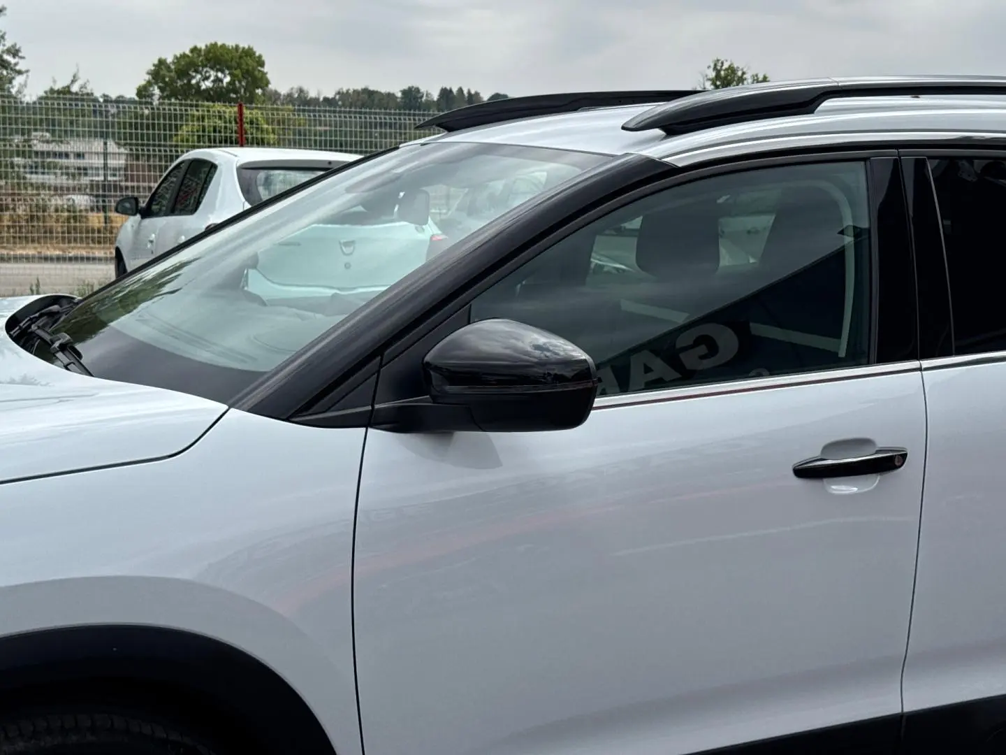 Vue de profil côté gauche sur le CITROEN C5 AIRCROSS blanc Okénite avec barres de toit et rétroviseur noir.