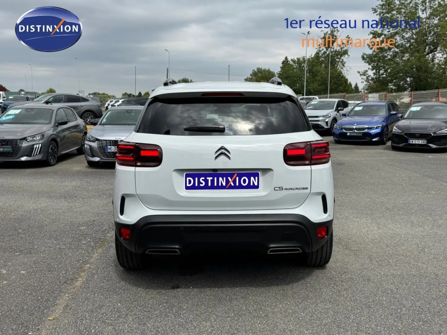 Vue arrière d'un Citroën C5 Aircross blanc Okénite avec feux arrière LED et barres de toit visibles.