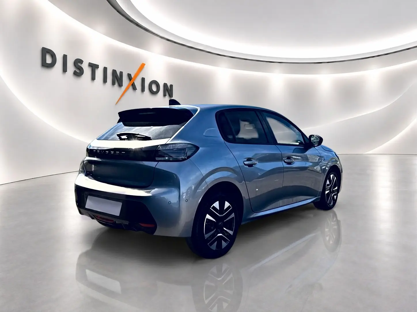Peugeot 208 gris artense vue 3/4 arrière droit dans un showroom lumineux avec jantes alu distinctives.