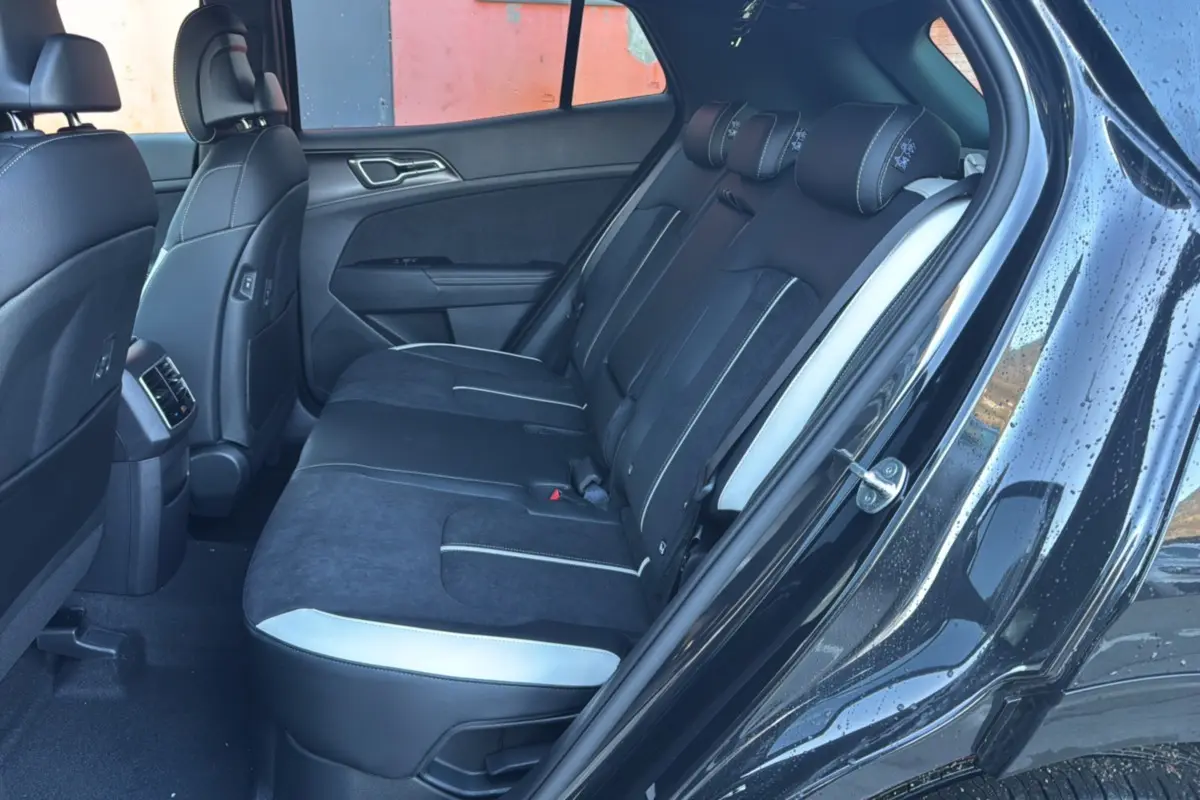 Vue côté droit de l’habitacle arrière du Kia Sportage noir étoilé, avec sièges en cuir noir et surpiqûres blanches.