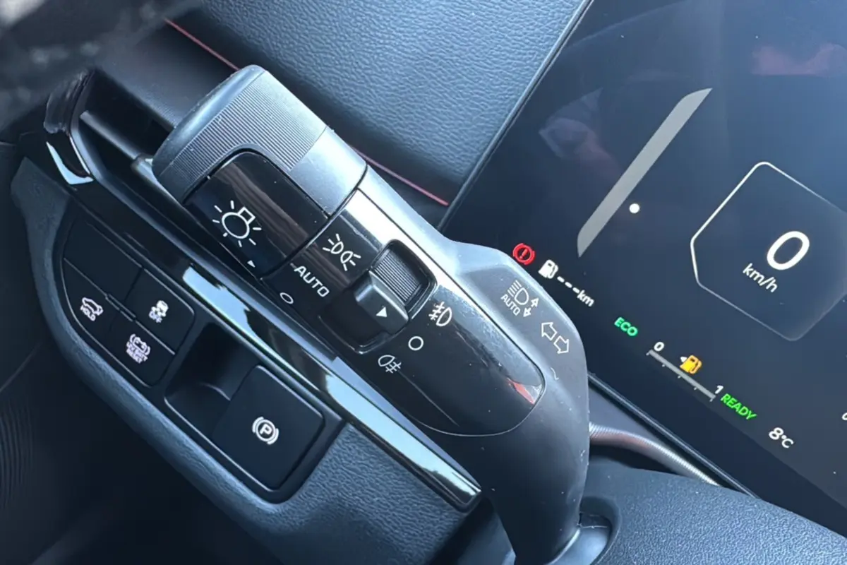Détail du commodo d'éclairage et frein à main électrique dans l'habitacle du Kia Sportage 2026 noir étoilé.