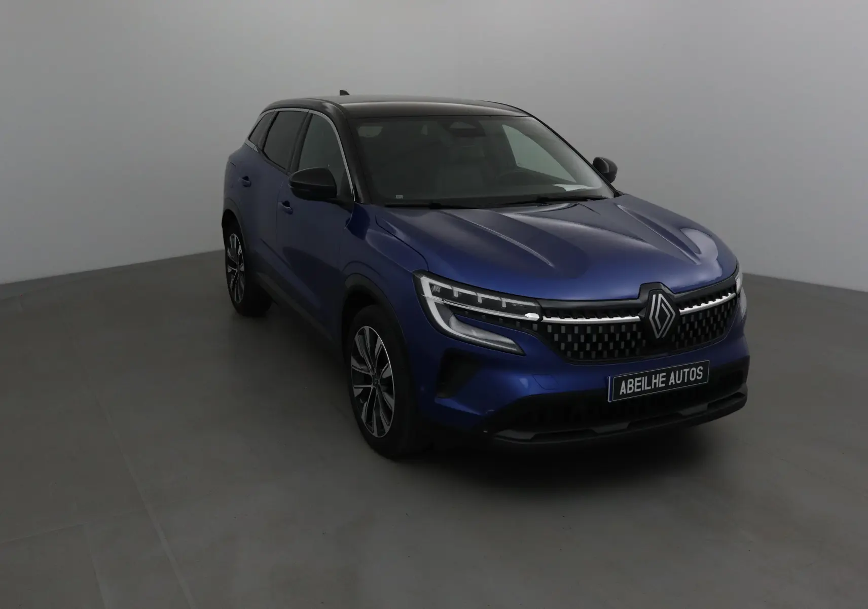 Renault Austral bleu Iron avec toit noir, vue 3/4 avant mettant en valeur sa calandre moderne et ses phares LED.