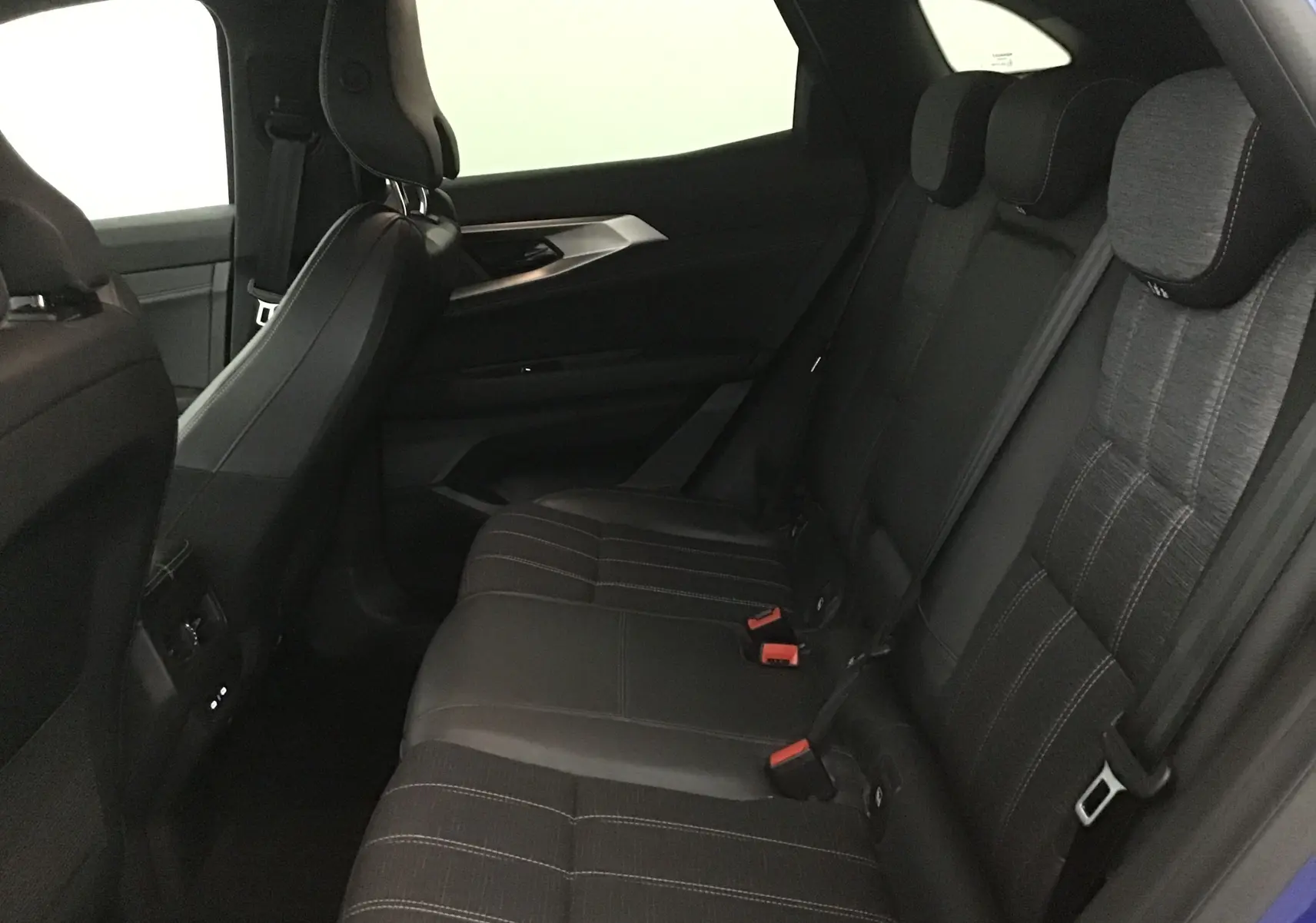 Vue latérale intérieure des sièges arrière noirs du Renault Austral 2023 bleu iron/ noir avec appuie-têtes et ceintures visibles.