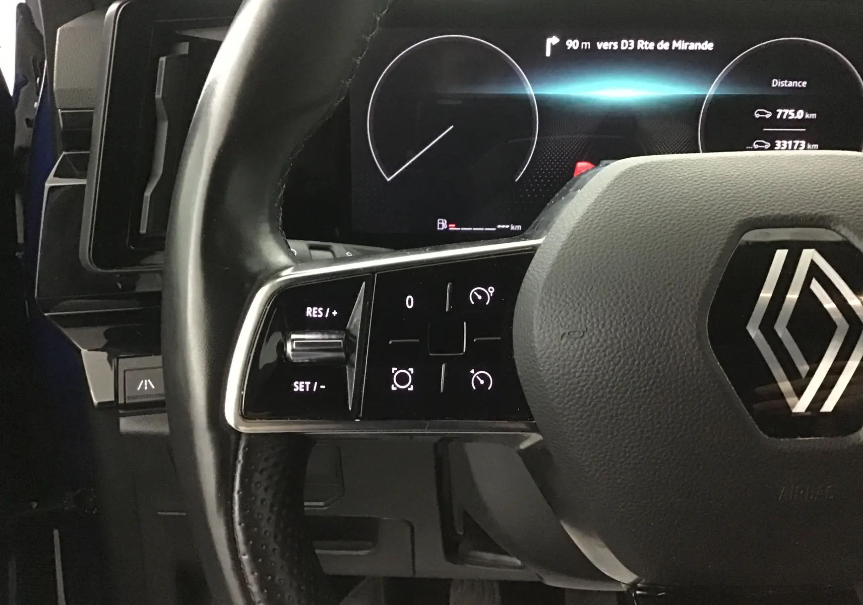 Gros plan sur le volant noir du Renault Austral 2023 avec commandes intégrées et tableau de bord numérique lumineux.