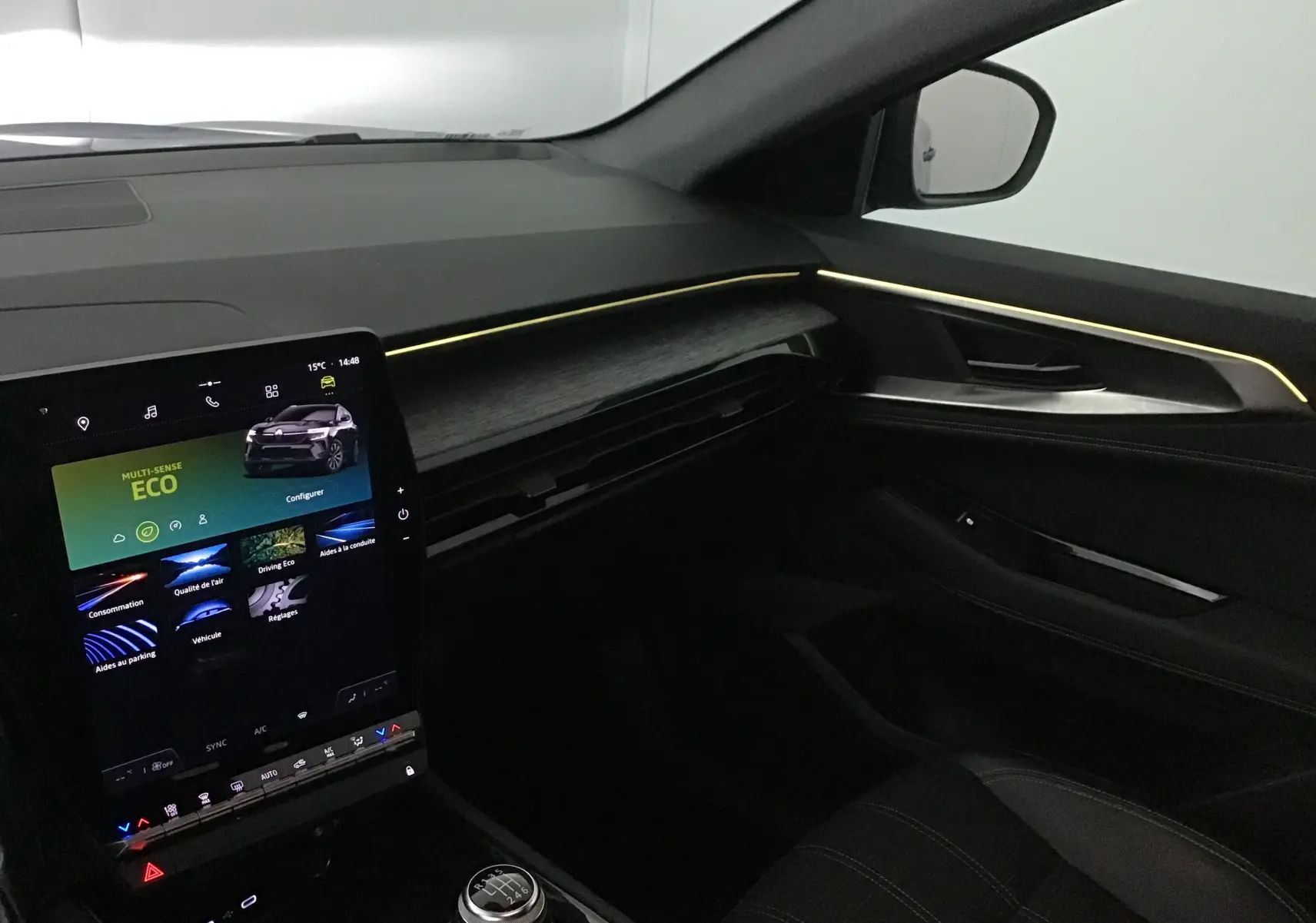 Intérieur côté passager du Renault Austral 2023 bleu iron/noir, avec écran tactile vertical et éclairage d'ambiance jaune.