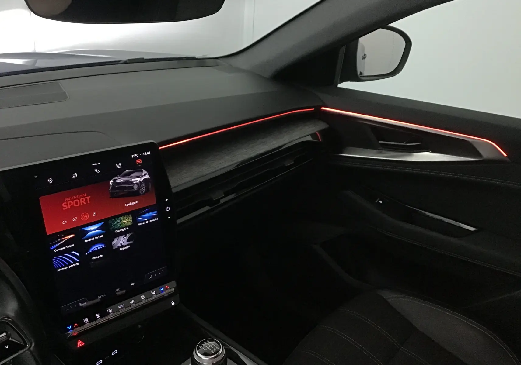 Intérieur côté passager du Renault Austral 2023 avec éclairage d'ambiance rouge et écran tactile vertical.