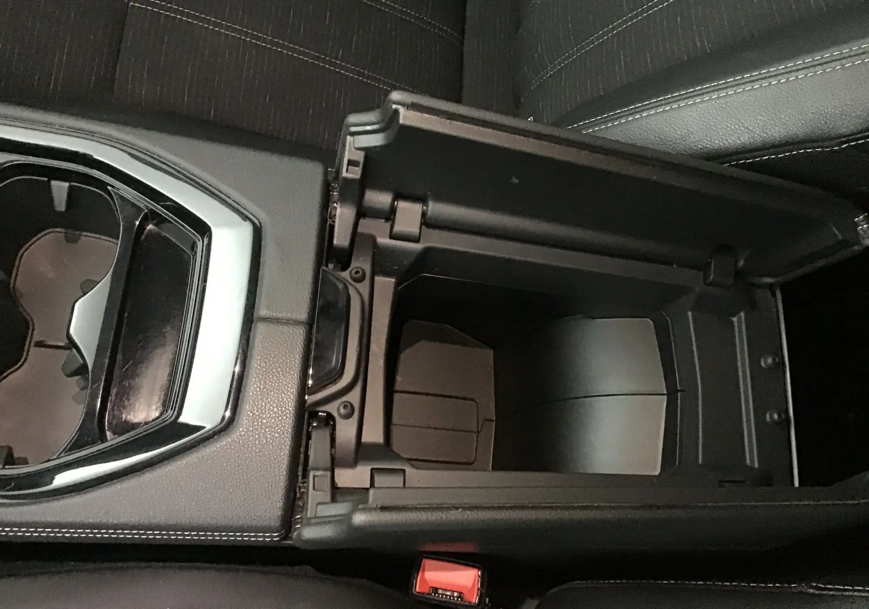 Vue plongeante sur la console centrale ouverte du Renault Austral 2023, avec porte-gobelets et sellerie noire.