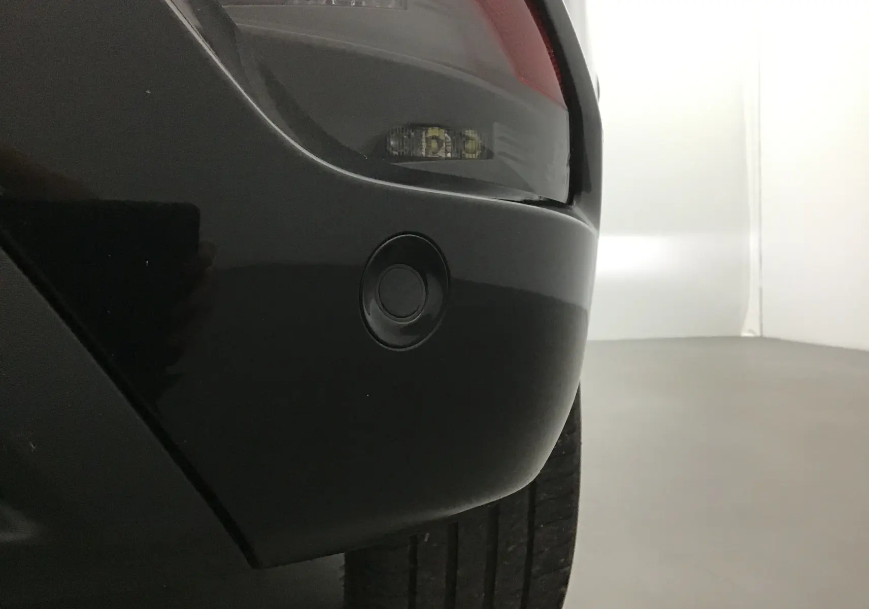 Gros plan sur le pare-chocs arrière côté droit du Renault Austral bleu iron/noir, avec feu arrière et capteur de stationnement visible.