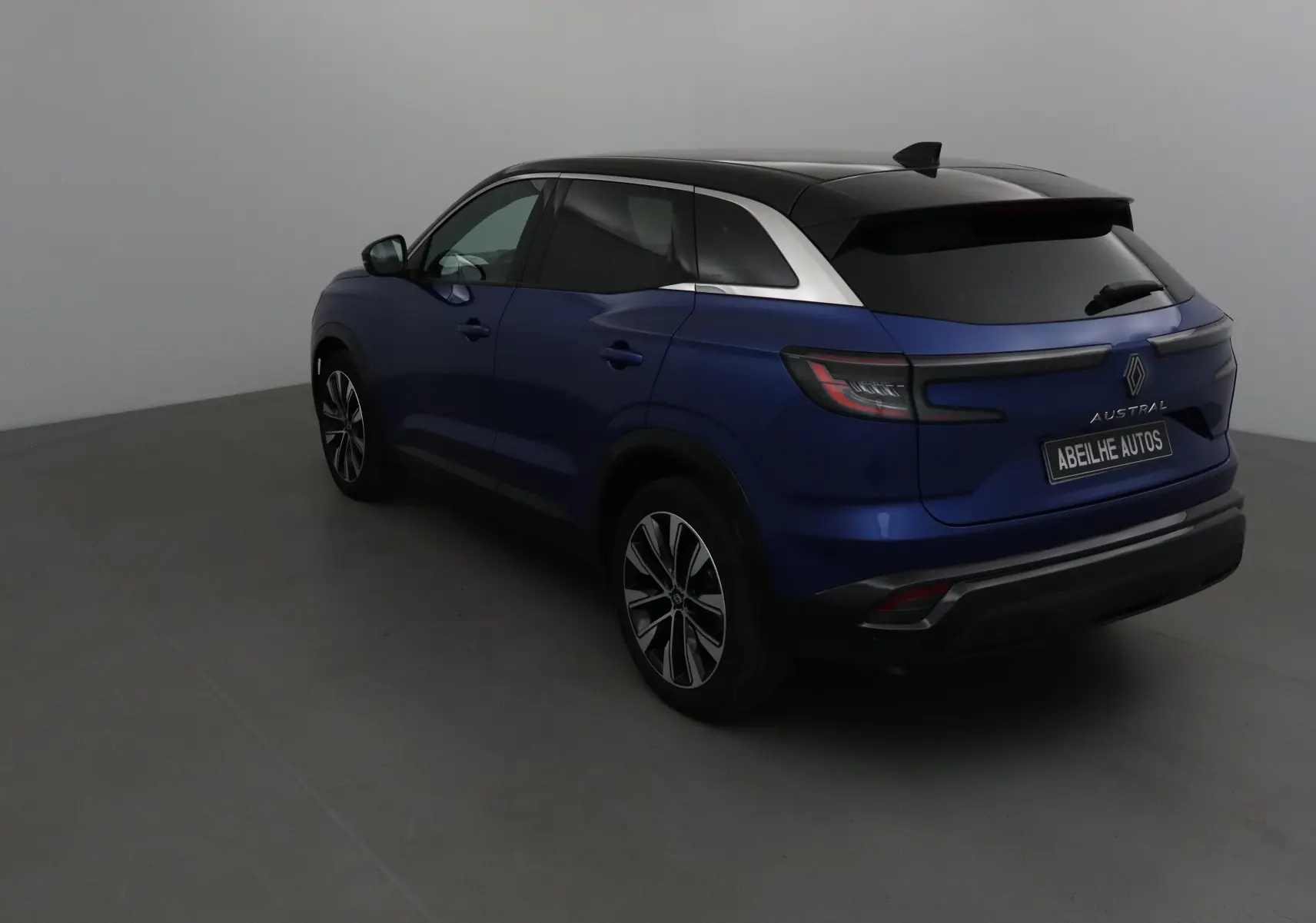 Renault Austral bleu Iron avec toit noir, vue 3/4 arrière côté gauche, jantes alliage et feux LED distinctifs.
