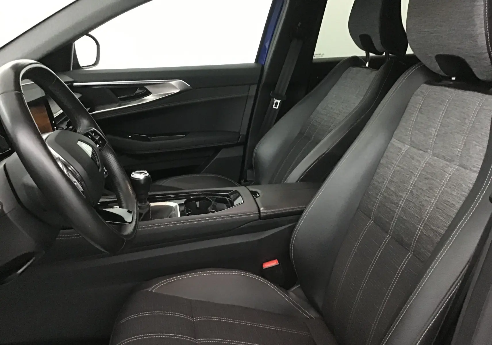 Intérieur avant droit du Renault Austral 2023, sièges tissu et cuir noirs, volant cuir et levier de vitesse manuel visibles.