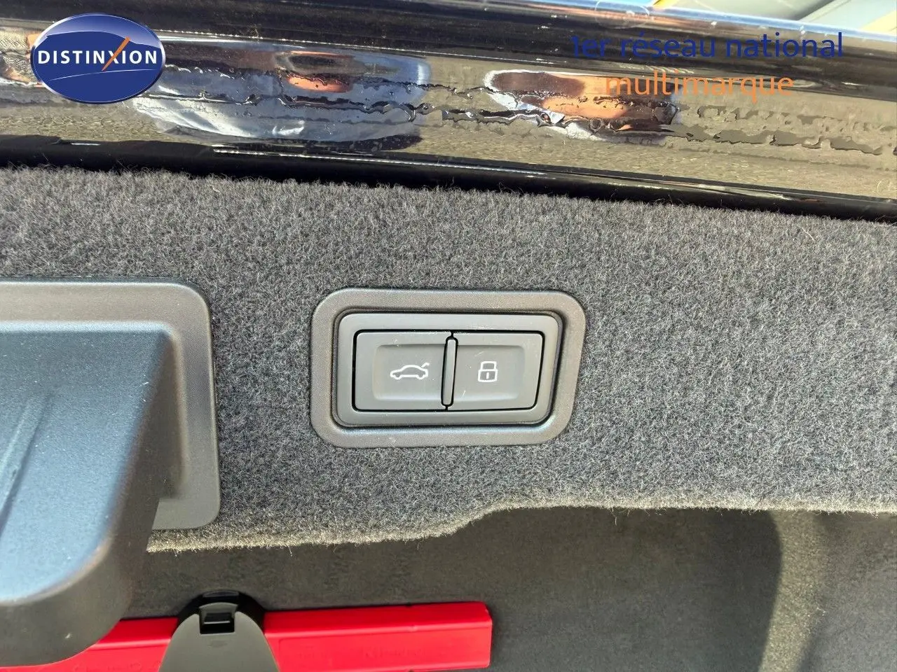 Gros plan sur les boutons d'ouverture et de verrouillage du coffre d'une Audi A8 noire Sebring Cristal, intérieur du coffre visible.