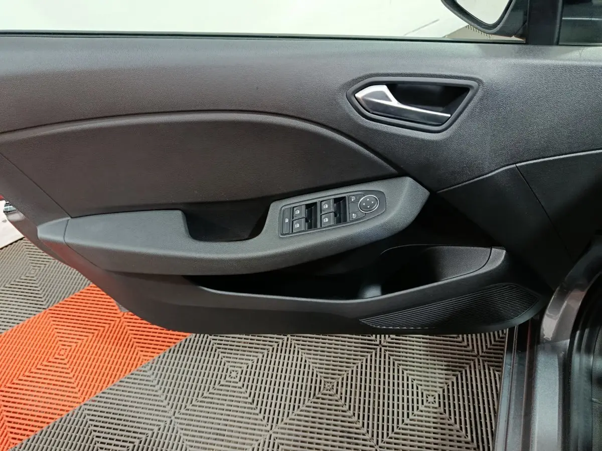 Vue intérieure côté gauche de la porte d'une Renault Clio gris foncé avec commandes de vitres et poignée argentée.