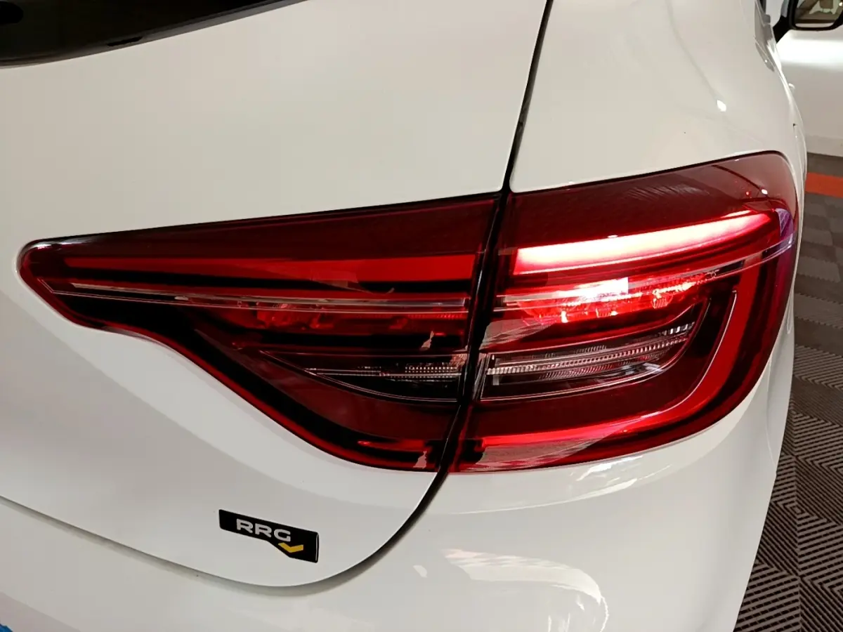 Gros plan sur le feu arrière droit rouge d'une Renault Clio Business Blue dCi 115 blanche, avec badge RRG visible.